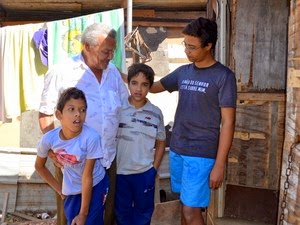 Pai adotivo carrega o filho doente nas costas por favela para levá-lo à escola José Manoel das Neves carrega o filho nas costas