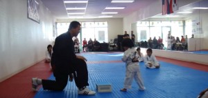 Garotinho tenta quebrar madeira em exame de faixa de Taekwon-Do